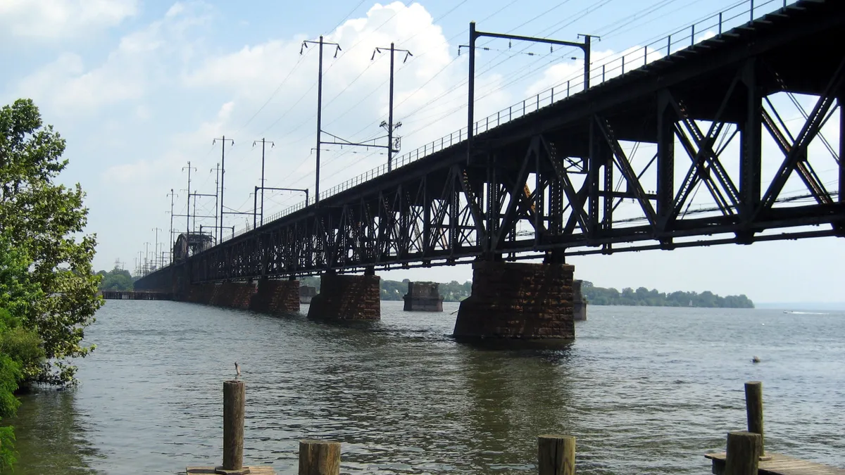 Waterfront view of a long open metal bridge.